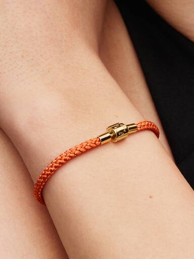 Skinnende orange armbånd med snor